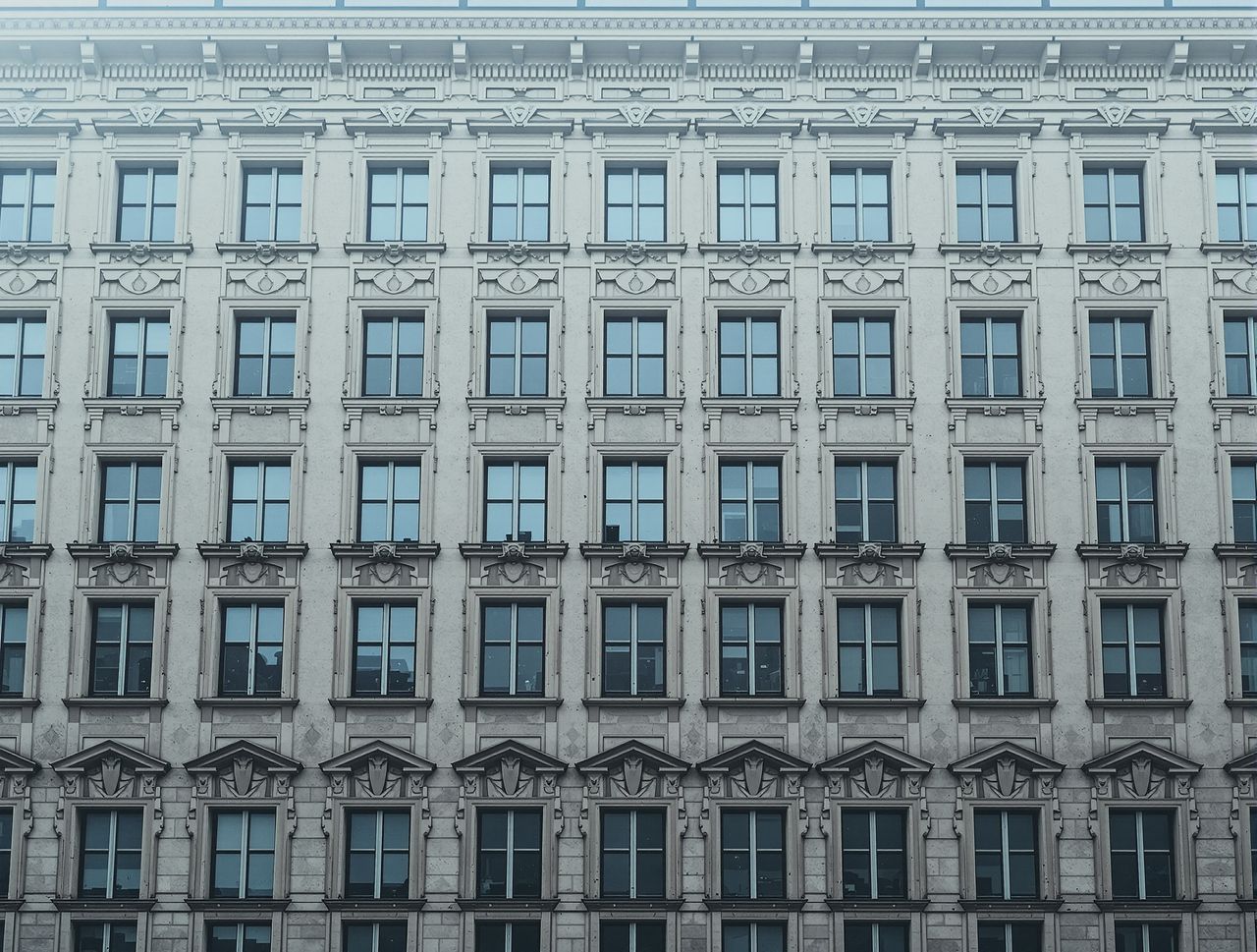 Die Fassade eines alten Wohnhauses im Nebel, viele gleiche hohe Fenster in einem Raster.